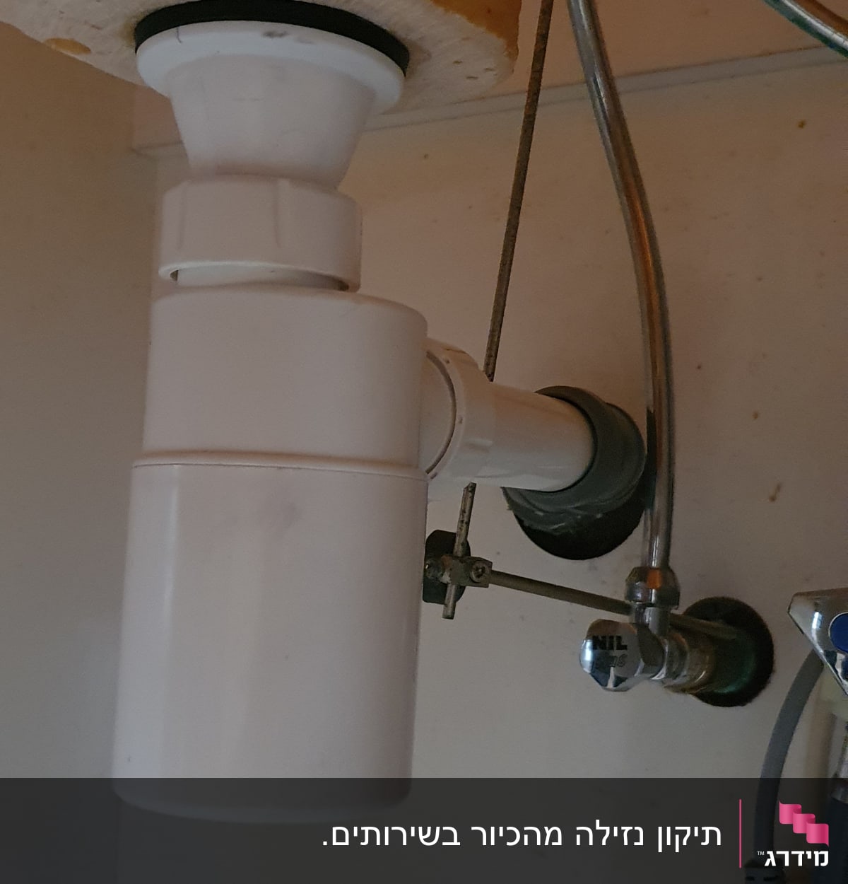 צינור ניקוז לבן מתחת לכיור עם ברזים